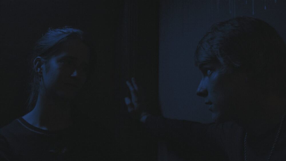 Two figures in blue night light at a window